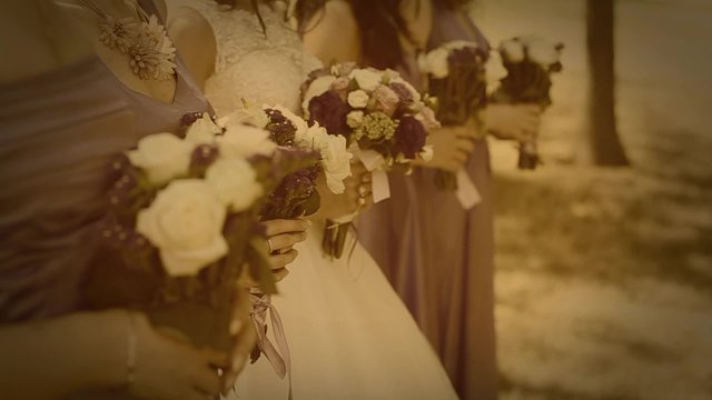 Wedding bouquets of flowers in hands of bride and bridesmaids. Wedding decor. Image toned in retro style. Vignette.  Video stylized as old movie with dots, dust, scratches.