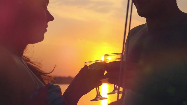Young happy couple in love kissing on yacht and drink wine with