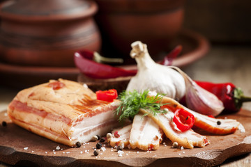 Smoked bacon, garlic, red pepper and salt on a wooden cutting bo