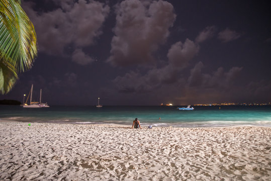 Plage de la Datcha, Le Gosier, Guadeloupe, la nuit, &eacute;clair&eacute;e, une femme pos&eacute;e sur le sable