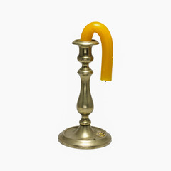 Candle in the old candlestick distorted by heat isolated on white background