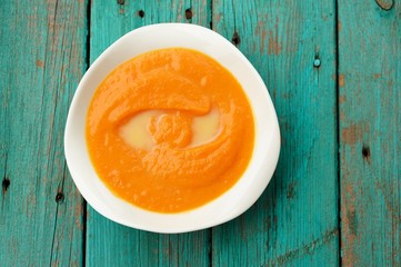 Homemade pumpkin soup puree with sesame seeds in white bowl on t