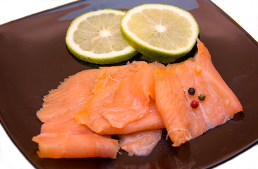 Smoked salmon on black plate on a white background seen close