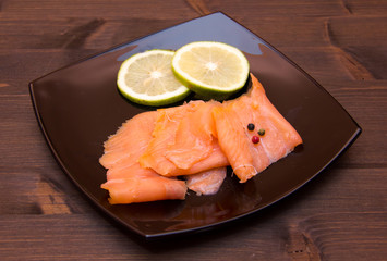 Smoked salmon on black plate on wooden table