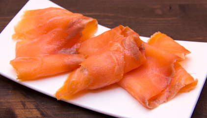 Smoked salmon on small tray on wooden table seen close