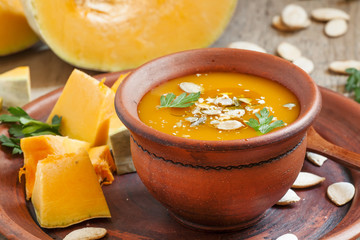 Pumpkin soup with oil and seeds in a clay bowl in a rustic style