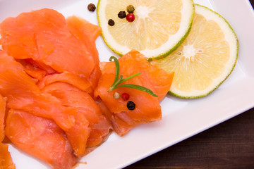 Smoked salmon on tray on wooden table seen from above and close