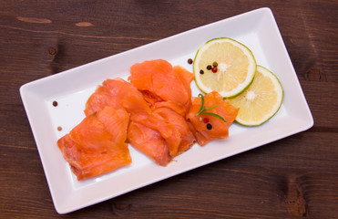 Smoked salmon on tray on wooden table seen from above