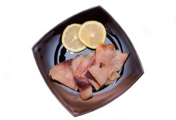 Smoked swordfish on black plate on a white background seen from above