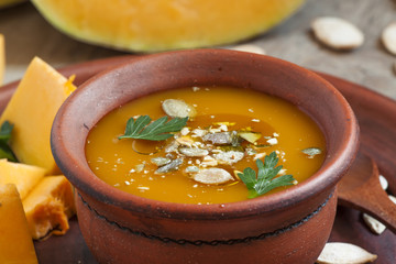 Pumpkin soup with oil and seeds in a clay bowl in a rustic style