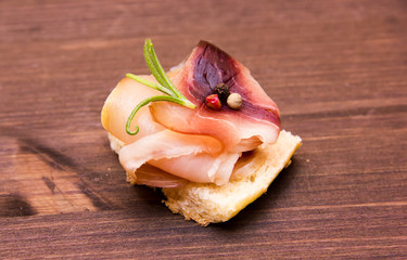 Smoked swordfish on toasted bread on wooden table
