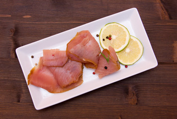 Smoked tuna on tray on wooden table seen from above