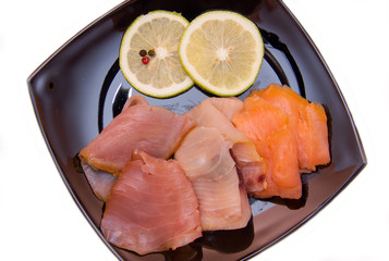 Trio of smoked fish on plate on white background seen from above and close