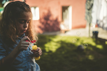 Fototapeta premium Little girl blowing soap bubbles outdoors