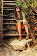 Funny young fashion girl sitting on the old wooden stairs.