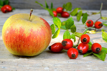 Rosehips with apple on an old wooden table