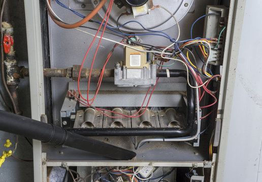 Repairman Vacuuming Inside Of A Gas Furnace