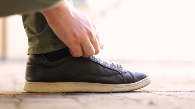 Male man lacing up shoes and walking away