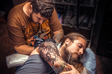 Man wearing gloves makes cool tattoo in tattoo parlour