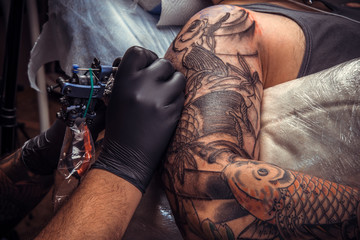 Master working tattooing in tattoo studio