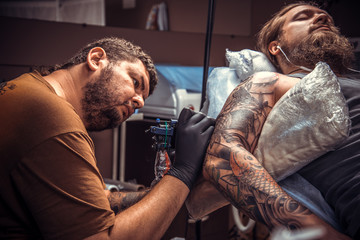 Professional tattooer showing process of making a tattoo in tattoo parlor