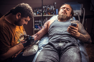 Tattooer makes cool tattoo in tattoo parlor