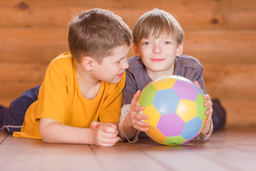Fototapeta premium Two friends with a ball lying on the floor