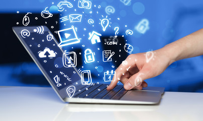 Hand writing on notebook computer with media icons and symbols