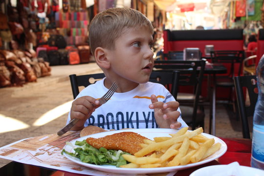 Breakfast in old city market in Jerusalem. Picture of a little boy, travel child,  seating in a street cafe in old city market in Jerusalem and taking a lazenge, flapjack, pita bread