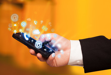 Business man holding smart phone with media icons