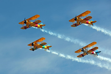 Four Biplanes Flying in Formation with Smoke