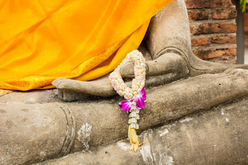 Jasmine and orchid flower garland on the hand of Buddha statue.
