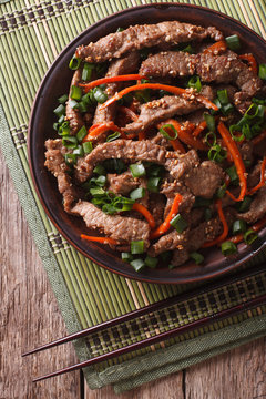Bulgogi beef slices fried with sesame close-up on a plate. vertical top view
