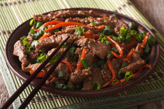 Asian cuisine: slices of beef fried with sesame and carrot close-up

