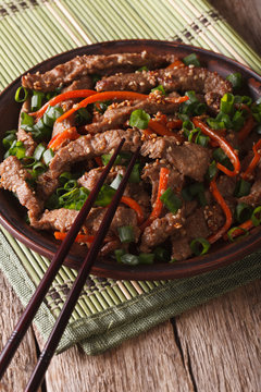 slices of beef fried with sesame seeds and carrots closeup. Vertical
