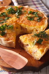 Sliced quiche with cheese, eggs and bacon close-up on a board. vertical
