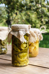 Pickled vegetables in preserving glass on wooden table