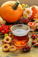 Glass of hot steaming tea and autumn plants on wooden table