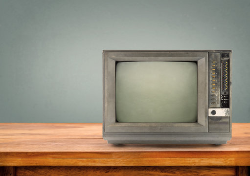 Retro television on wood table with vintage  wall background