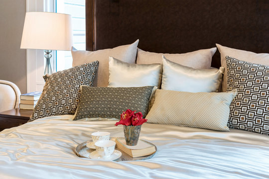 luxury bedroom interior with brown pattern pillows and decorative tray of flower on bed