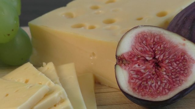 Yellow cheese and fresh figs on the wooden cutting board 
