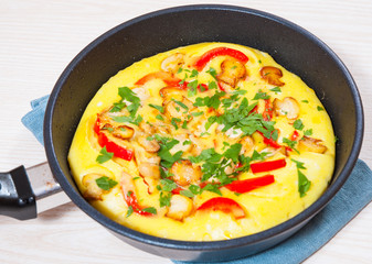omelet with mushrooms, and vegetables in a frying pan