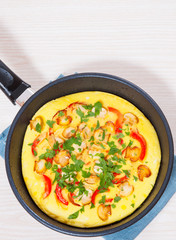omelet with mushrooms, and vegetables in a frying pan