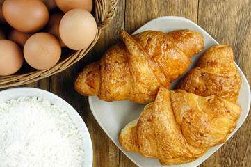 Croissant with eggs and flour on rustic wooden table