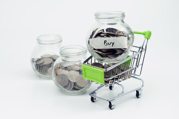 Coins in small container and shopping cart with label Buy - fina