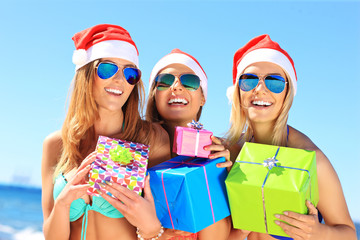 Group of girls in Santa's hats having fun on the beach