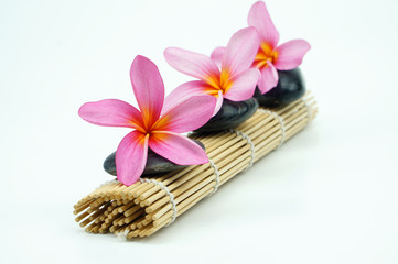 Fototapeta na wymiar Pink Frangipani on pebble and bamboo mat. Spa concept