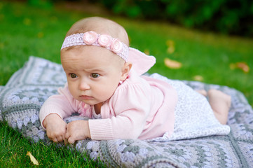 beautiful little baby girl is lying on a plaid blanket