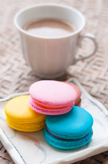 white cup of frothy espresso coffee with colourful French macaroon