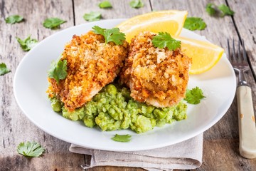 Baked cod fish in breadcrumbs with mashed green peas and broccoli